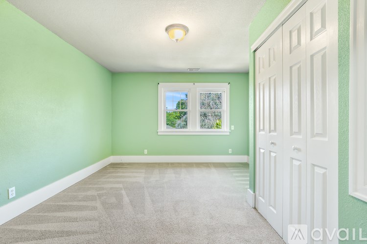 A room with green walls and a window with a view of trees and a blue sky.