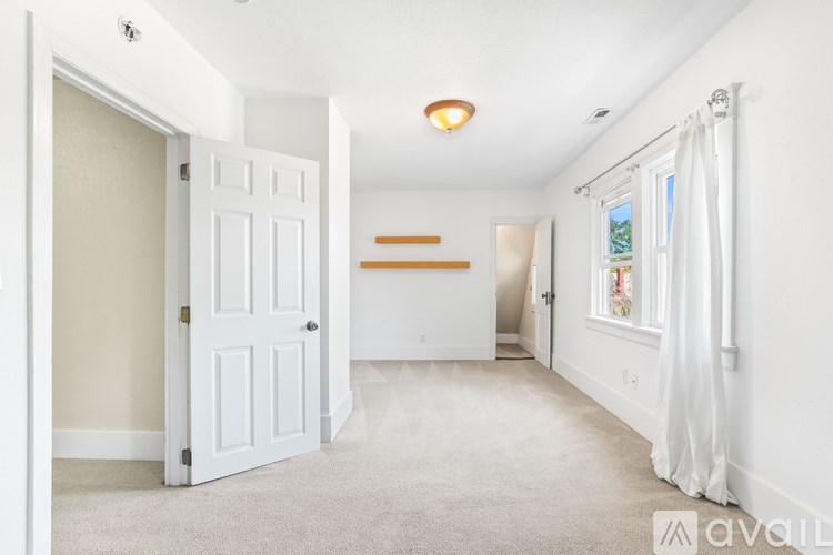 A white door is open to a hallway with a carpeted floor.