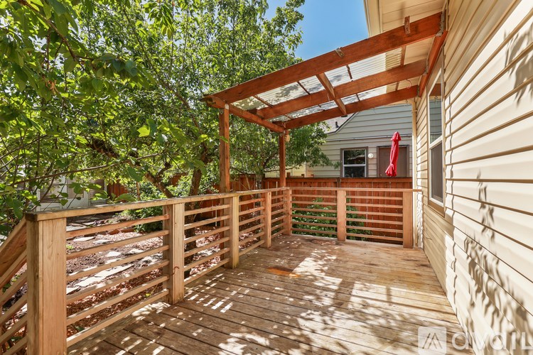 A wooden deck with a pergola and a red umbrella.