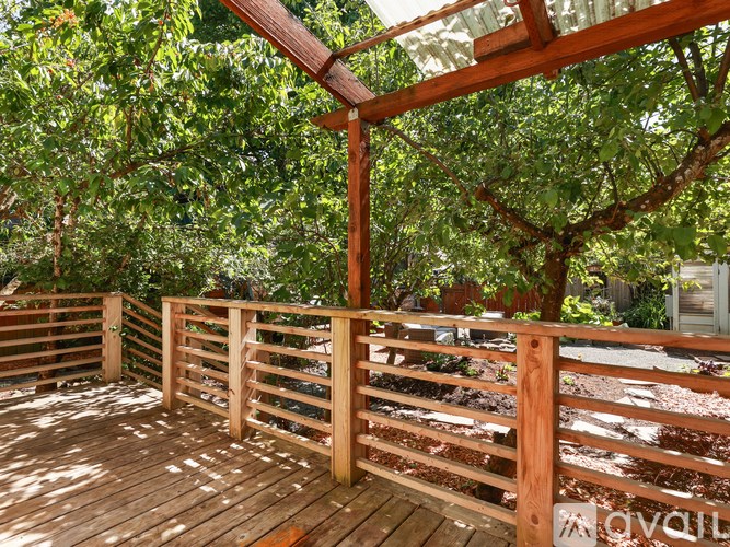 A wooden deck with a railing and trees in the background.