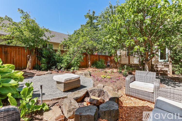 A backyard with a hot tub, trees, and a wooden fence.