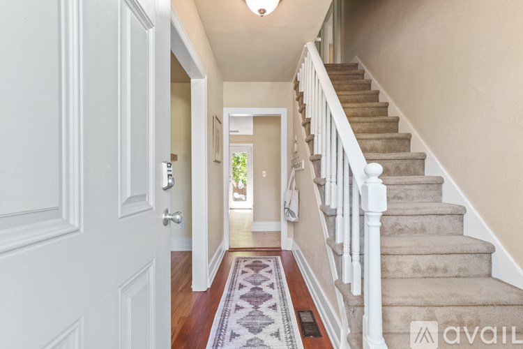 A hallway with a staircase and a rug on the floor.