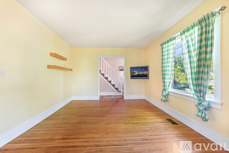 A room with wooden floors and a staircase leading to another room.