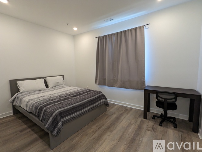 A bedroom with a bed, desk, and chair.