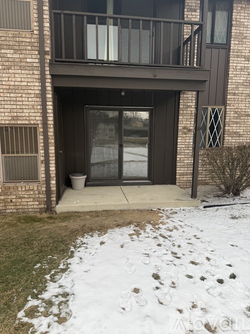 A snow-covered ground in front of a building with a glass door.