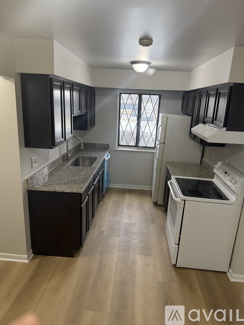 A kitchen with black cabinets and a white dishwasher.