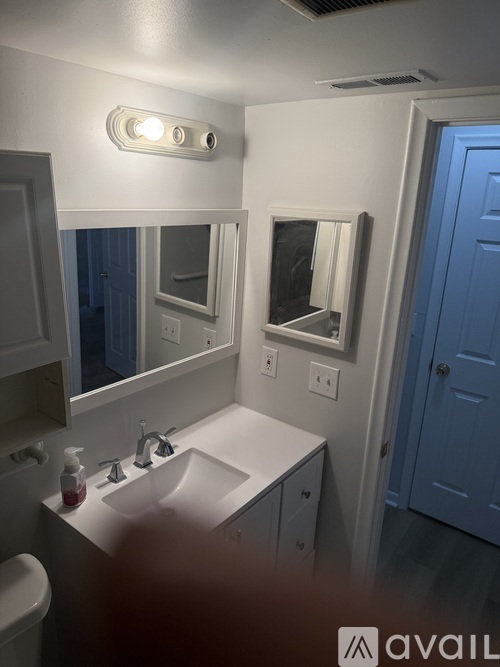 A bathroom with a white sink and mirror.