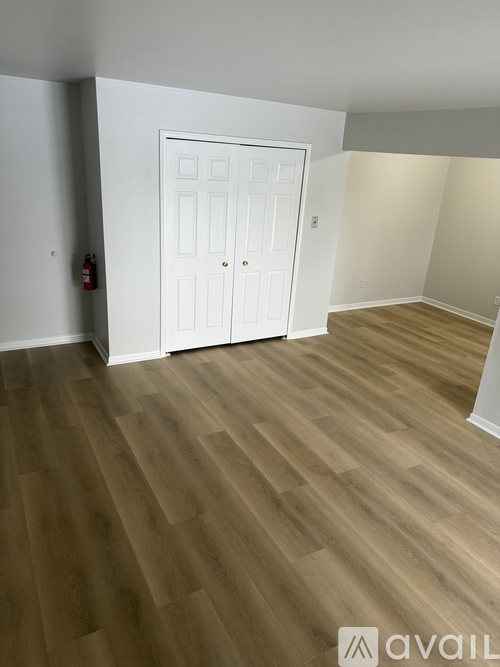 A room with a white door and wooden flooring.