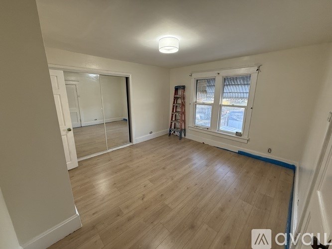A room with wooden flooring and a ladder against the wall.