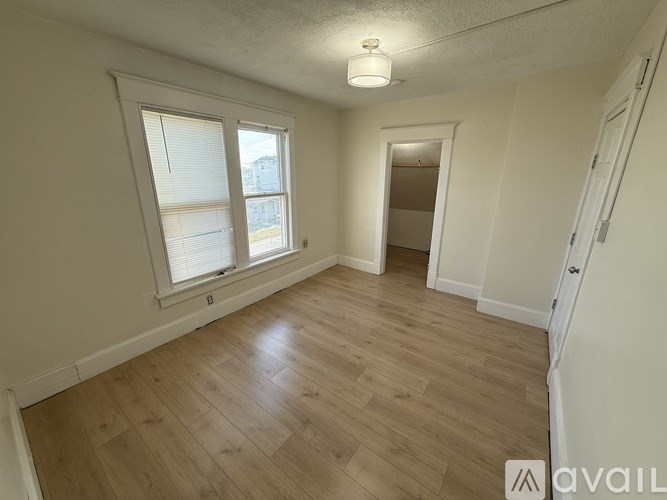 A room with wooden flooring and a window with blinds.