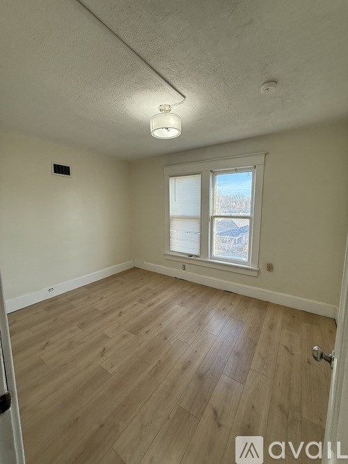 A room with wooden flooring and a window showing a view of a snowy landscape.