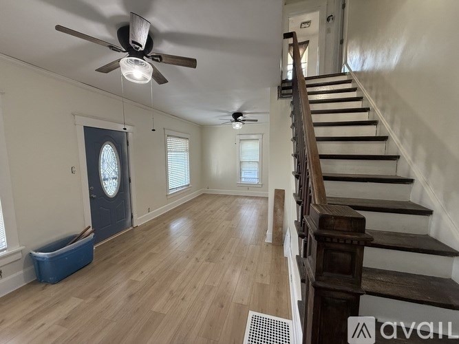 A room with wooden floors and a staircase leading to another room.