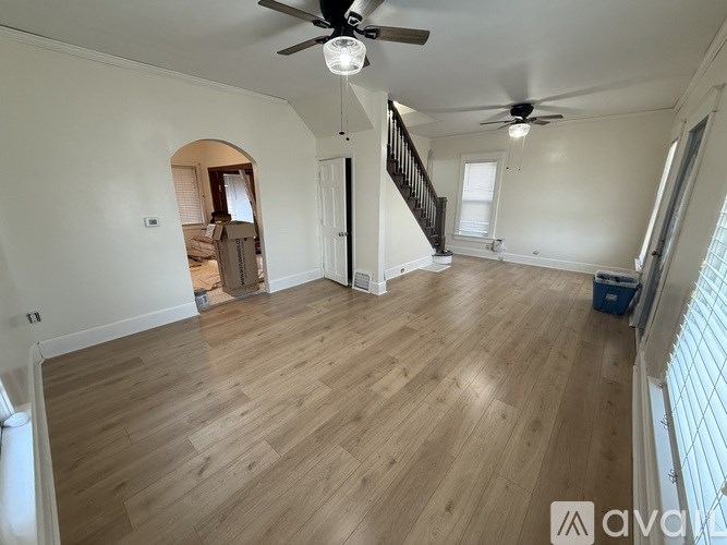 A spacious room with wooden flooring and a ceiling fan.