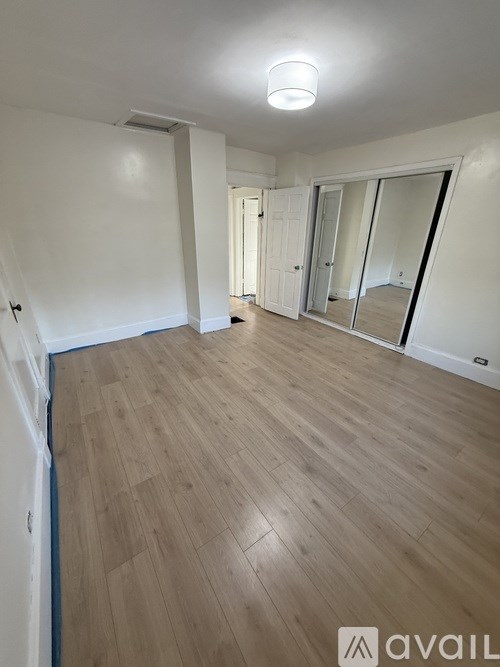 A spacious room with wooden flooring and white walls.