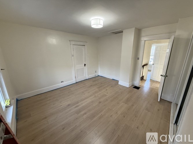 A spacious room with wooden flooring and white walls.
