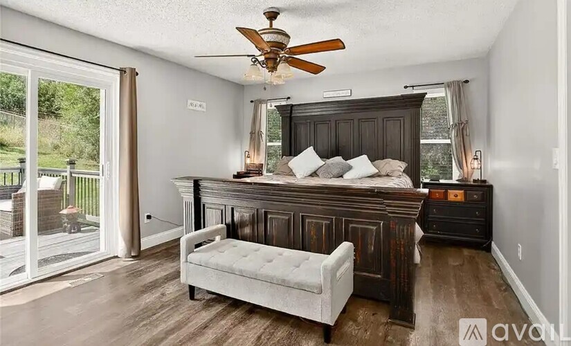 A bedroom with a bed, a bench, and a ceiling fan.