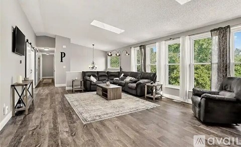 A living room with a black couch and a television on the wall.