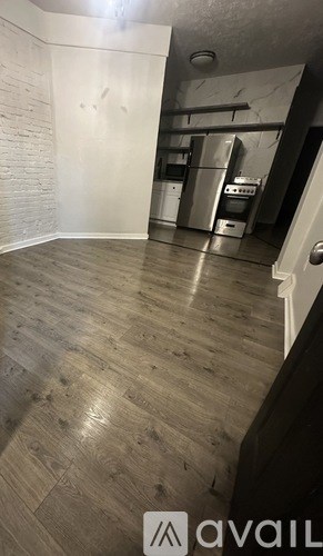 A kitchen area with wooden flooring and a white wall.