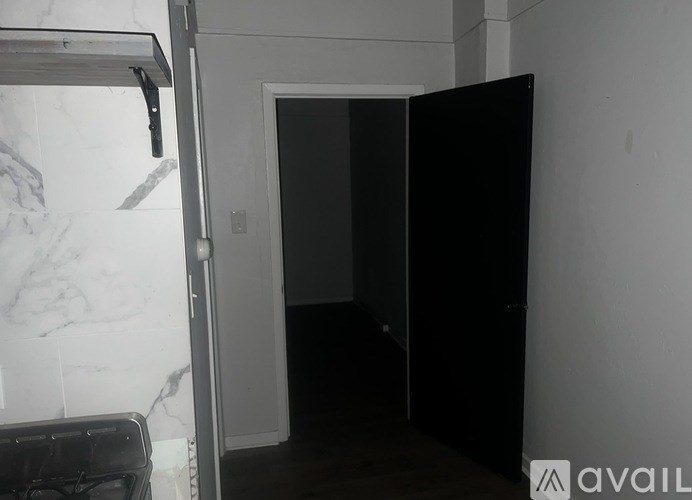 A black wardrobe stands in a room with a marble wall.