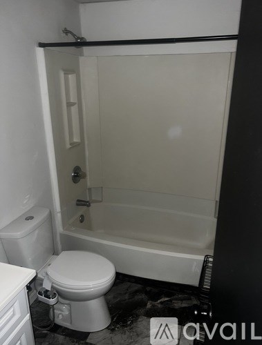 A white toilet in a bathroom with a white tub.