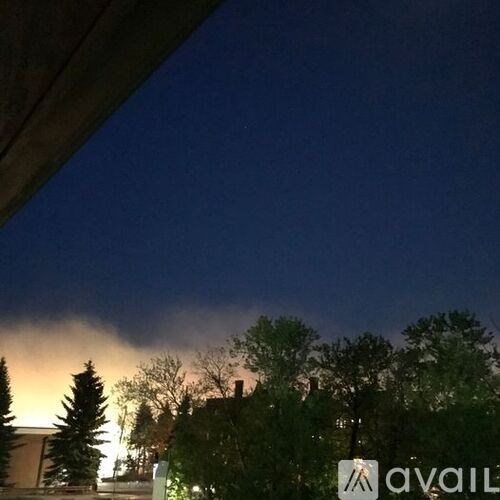 A dark sky with clouds and trees in the foreground.