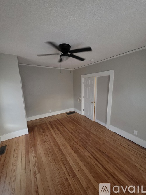 A room with a ceiling fan and wooden flooring.
