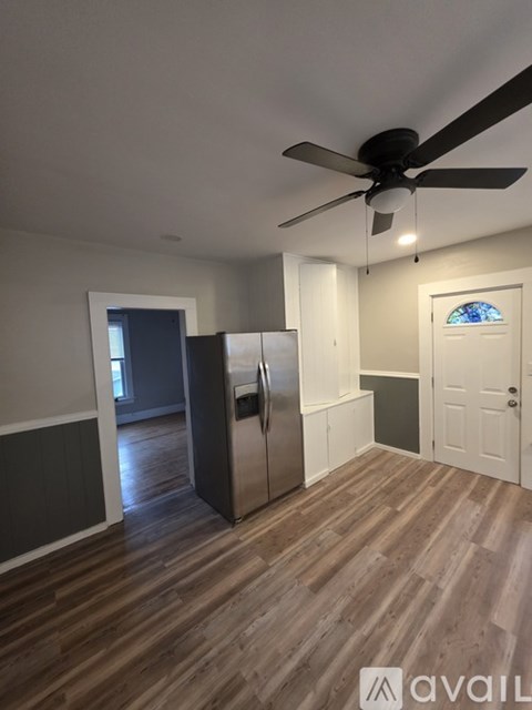 A kitchen with a refrigerator and a ceiling fan.