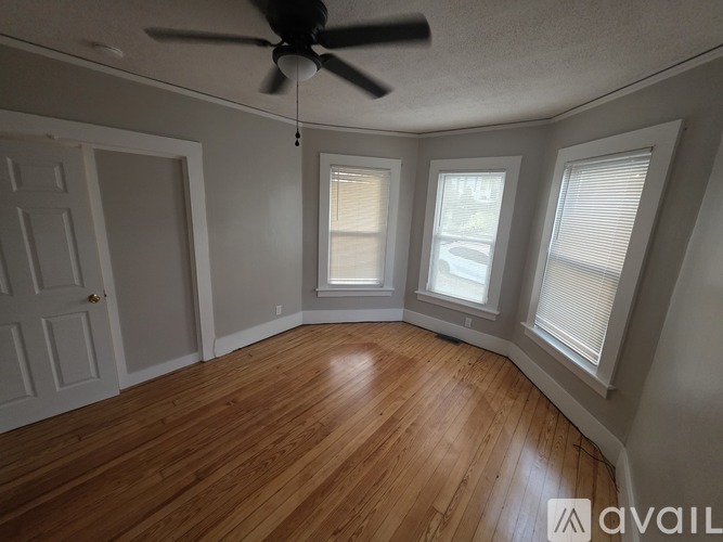 A room with a ceiling fan and wooden flooring.