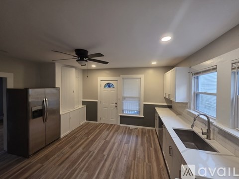 A kitchen with a refrigerator, sink, and wooden floors.