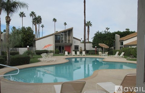 A pool with chairs around it and a house in the background.