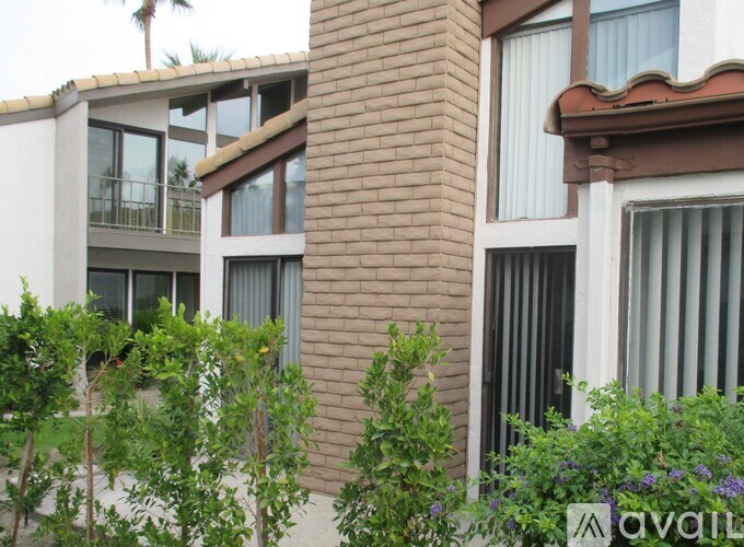 A building with a balcony and a tree in front of it.