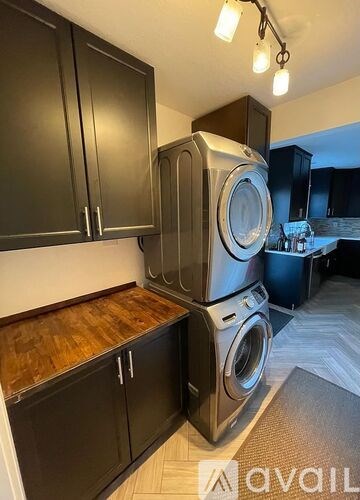 A stack of washing machines in a laundry room with black cabinets.