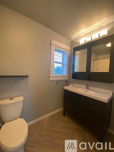 A bathroom with a toilet, sink, and mirror.