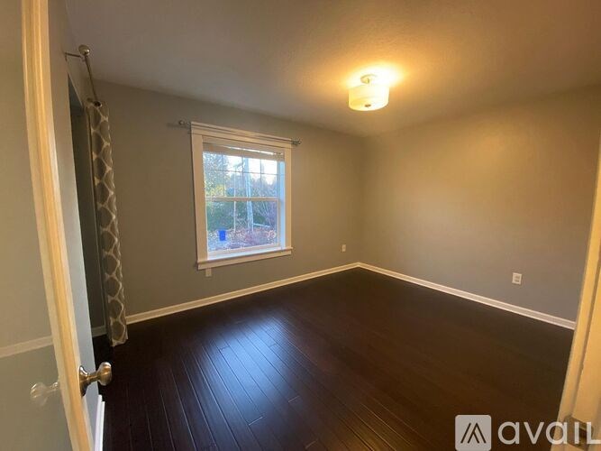 A room with a window and a wooden floor.