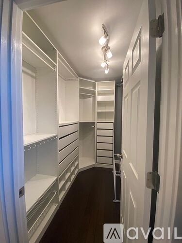 A long hallway with white shelves and a light on the ceiling.