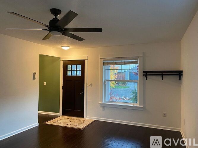 A room with a ceiling fan and a window overlooking a backyard.