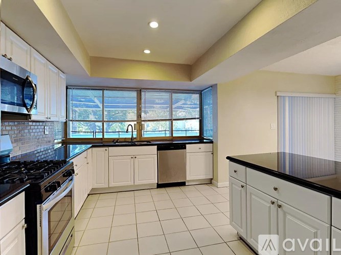 A kitchen with black countertops and white cabinets.