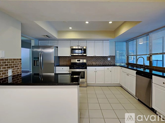 A kitchen with white cabinets and a black countertop.