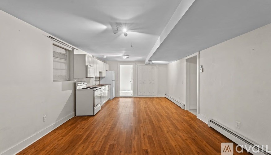 A long, empty room with wooden floors and white walls.