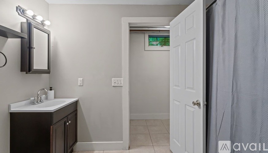 A bathroom with a sink, mirror, and a door.