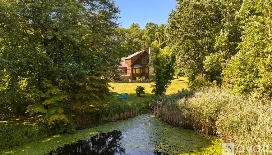 A house is surrounded by greenery and a small pond.