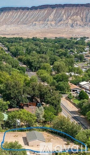 A bird's eye view of a residential area with a road and a house with a blue line drawn around it.