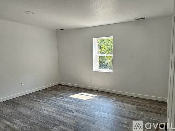 A room with a window and wooden flooring.