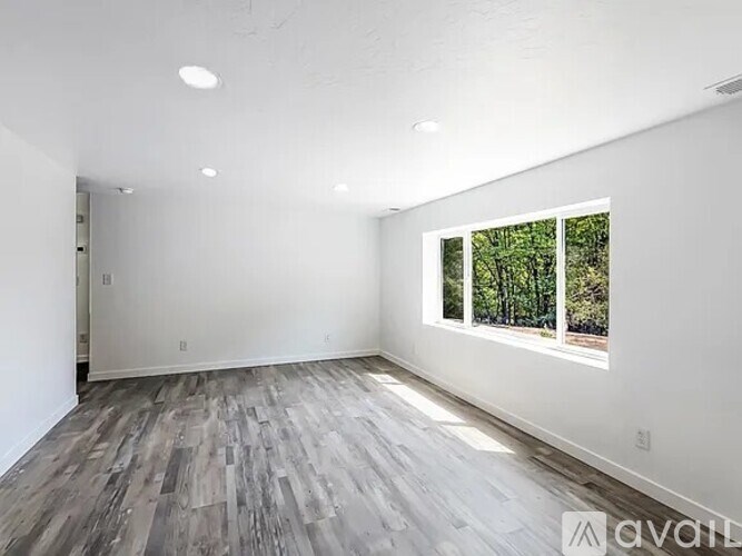 A room with a window and wooden flooring.