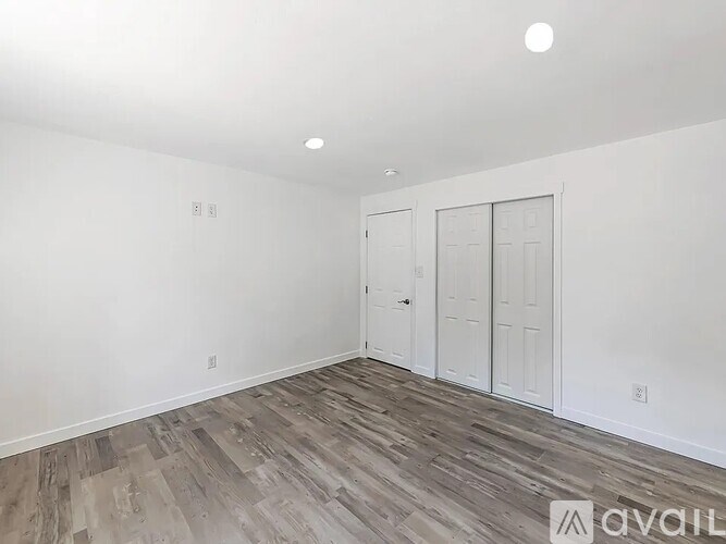 A room with a white wall and a wooden floor.