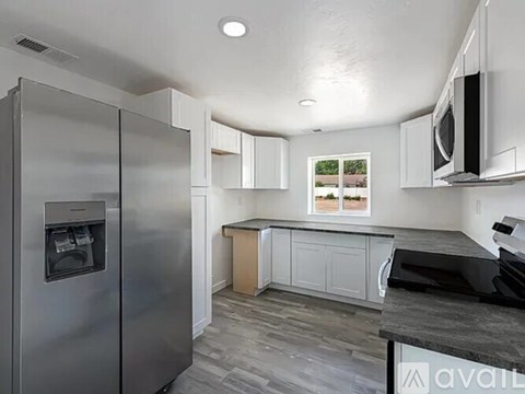 A kitchen with a stainless steel refrigerator and a black countertop.