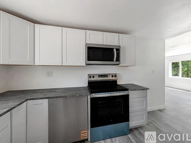 A kitchen with white cabinets and a black countertop.