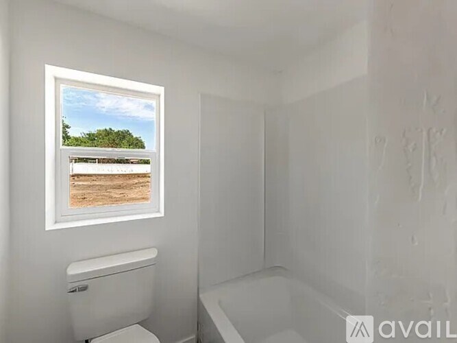 A bathroom with a toilet, a bathtub and a window with a view of a beach.