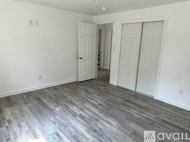 A room with a grey floor and white walls with two doors.