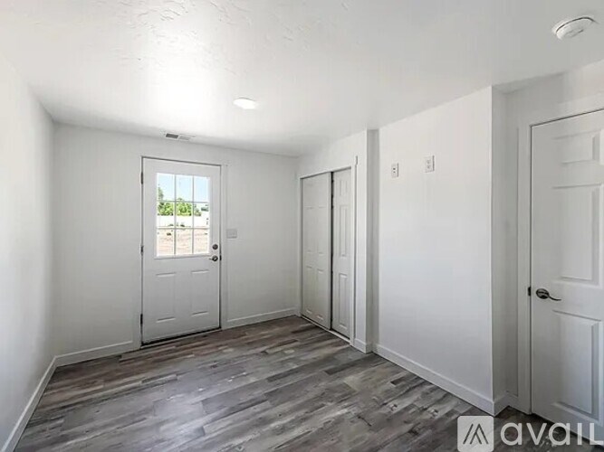 A room with a door, a window, and a wooden floor.
